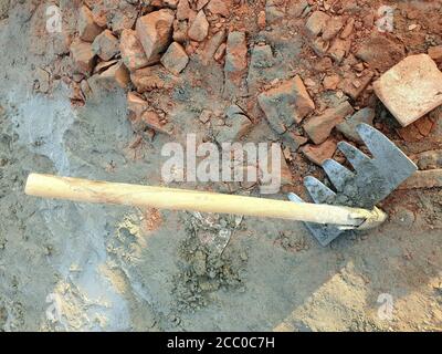 Uomo che indossa guanti da giardinaggio erbacce il terreno con le mani e  una mano zappa vicino a un largo bean di fila Foto stock - Alamy