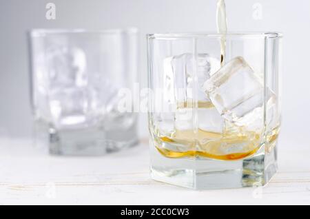 Due bicchieri di scotch whiskey con cubetti di ghiaccio, sfondo bianco, sfondo in legno Foto Stock