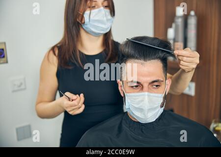 Donna attenta che combatte i capelli del suo cliente Foto Stock