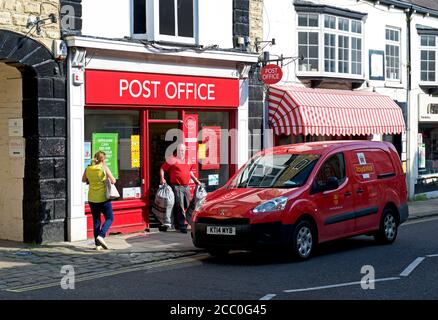 Postino che raccoglie i sacchetti di posta dall'ufficio postale su High Street, Wetherby, West Yorkshire, Inghilterra Regno Unito Foto Stock