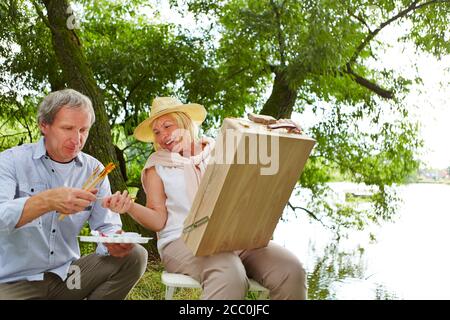 La vecchia donna e l'anziano dipingono un quadro in natura in estate Foto Stock