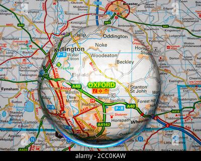Primo piano di una lente d'ingrandimento a forma di cupola su una pagina di una mappa dell'atlante stradale britannico, con l'area di Oxford in Inghilterra ingrandita per una vista più ravvicinata. Foto Stock
