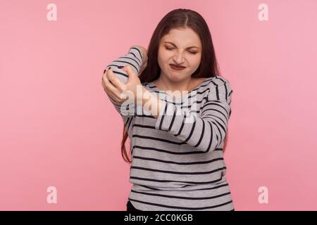 Lesioni alle mani. Ritratto di donna che massaggiano gomito dolorante, accigliato da dolore acuto, sforzo e problema di sforzo, nervi intrappolati, artrite reumatoide Foto Stock