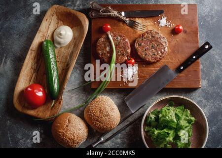 Carne di manzo macinata grezza bistecca di hamburger con ingredienti sulla tavola. Foto Stock