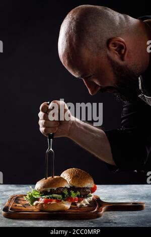 Lo chef prepara hamburger al ristorante. Foto Stock