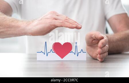 Simbolo heartbeat protetto dalle mani - concetto di assicurazione sanitaria Foto Stock