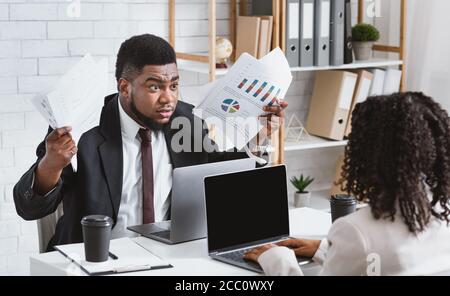 Furioso uomo afroamericano che combatte con la sua collega in ufficio, spazio vuoto Foto Stock