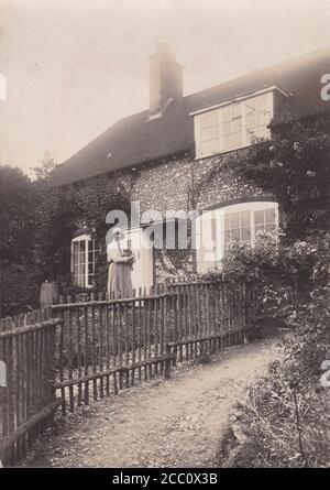 Foto vintage in bianco e nero di una giovane donna in piedi nel giardino anteriore del 1900 Foto Stock