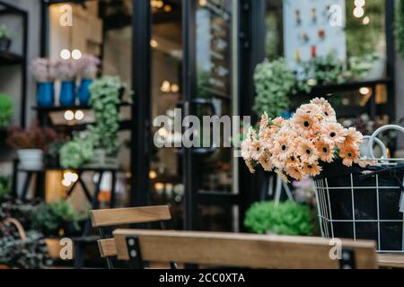 Realizzazione di decorazioni in studio di design floreale. Panna margherite in cestino sul tavolo in negozio di fiori Foto Stock