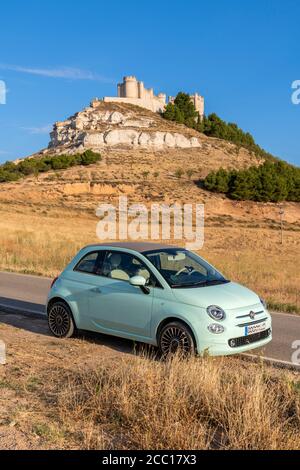 Fiat 500 auto parcheggiata in una strada rurale con un castello medievale sullo sfondo, Penafiel, Castiglia e Leon, Spagna Foto Stock