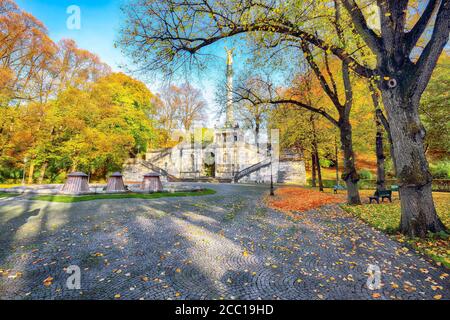 Incantevole vista autunnale dell'Angelo della Pace (Friedensengel) monumento. Statua di un angelo dorato su una colonna nel parco cittadino. Località: Monaco, Baviera, Germania Foto Stock