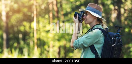 fotografia naturalistica - fotografo donna che fotografa con una fotocamera analogica in foresta. spazio copia banner Foto Stock