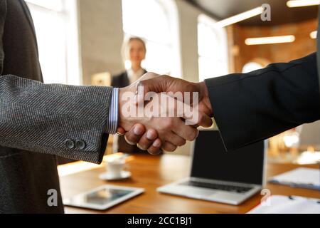 Primo piano di uomini d'affari che scuotono le mani nella sala conferenze, facendo un affare, un accordo di successo o la cooperazione. Concetto di finanza e business, contratti, partnership, comunità e lavoro di squadra. Foto Stock