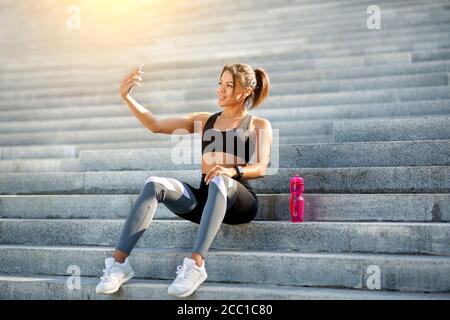 Donna nera positiva sport blogger prendendo selfie mentre si esercita Foto Stock