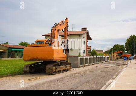 Escavatore cingolato con piattaforma girevole e cingolo continuo caterpillar con cassoni in cemento armato. Sito di sostituzione delle acque reflue, Italia Foto Stock