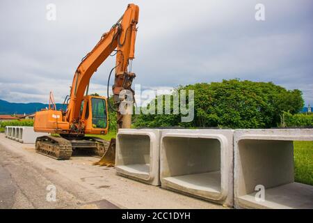 Escavatore cingolato con piattaforma girevole e cingolo continuo caterpillar con cassoni in cemento armato. Sito di sostituzione delle acque reflue, Italia Foto Stock