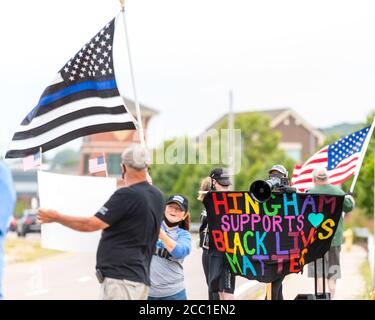 Black Lives Matters i manifestanti che tengono segni e urlano su un megafono contro persone che detengono una bandiera della linea blu sottile a sostegno della polizia locale. Foto Stock