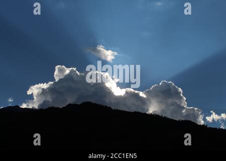 Sole tra le nuvole sulla cima di una montagna Foto Stock