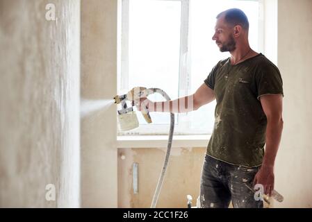 Lavoratore con aerografo verniciatura House riparare la vernice della porta  di legno di colore bianco con una bomboletta spray Foto stock - Alamy