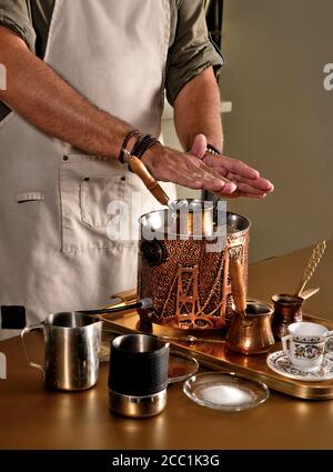 Caffè turco tradizionale estratto in sabbia riscaldata. Processo di preparazione da parte di un barista. Foto Stock