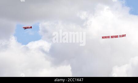 1961 Piper Super Cub Airborne all'Airshow di Shuttleworth Drive-in Il 2 agosto 2020 trainare una bandiera aerea con il messaggio rimuovere Prima del volo Foto Stock