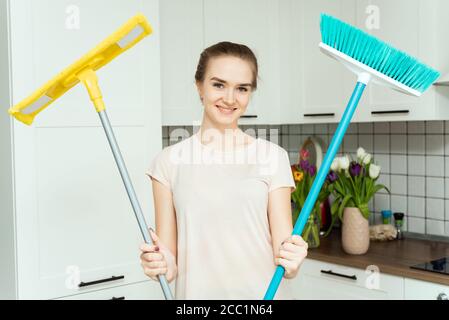 Una giovane donna sta tenendo il mop. Donna è pronta a pulire casa. Una casalinga è la casa di pulizia e sorridente. Foto Stock