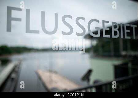 17 agosto 2020, Nord Reno-Westfalia, Essen: 'Bacino fluviale' è scritto su un disco, mentre sullo sfondo si può vedere il lago Baldeney. La messa in servizio ufficiale del primo sistema di sollevamento del pesce nella Renania Settentrionale-Vestfalia si svolge presso la centrale idroelettrica del lago Baldeney di Essen. Il doppio ascensore è destinato a consentire ai pesci di salire senza ostacoli sul fiume. Foto: Fabian Strauch/dpa Foto Stock