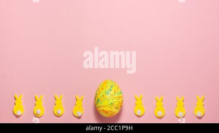 Coniglietti di velluto giallo e uovo di pasqua su sfondo rosa in fondo con spazio per la copia. Vista dall'alto in posizione piatta. Concetto di Pasqua Foto Stock