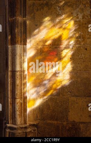 Concept religione; una vetrata che getta una luce colorata sulle pareti medievali dei chiostri, Tours cattedrale, Tours Francia Foto Stock