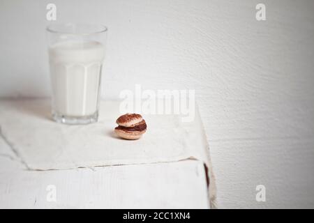 Macarons con glassa al cioccolato e un bicchiere di latte Foto Stock