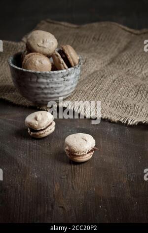 French Macarons riempito con glassa al cioccolato in tazza Foto Stock