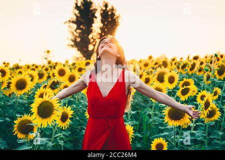 Bella donna con capelli lunghi in un campo di girasoli. Attivo, sollevamento Foto Stock