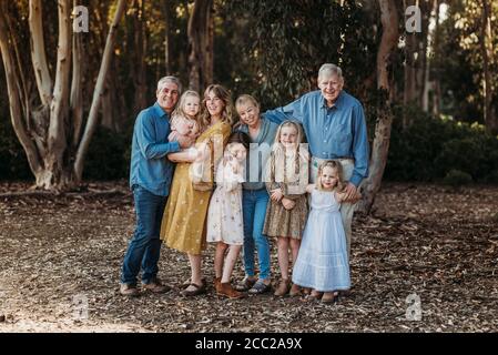 Ritratto di una grande famiglia allargata sorridente che abbraccia l'esterno nella foresta Foto Stock