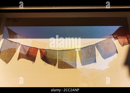 Il sole getta ombre di tradizionali bandiere di preghiera buddista su un schermo vento Foto Stock