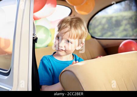 In Germania, in Renania settentrionale-Vestfalia, Colonia, ragazzo seduto in auto, guardando lontano Foto Stock