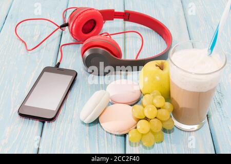 Il marshmallow si trova accanto al telefono, le cuffie rosse e una tazza di cappuccino. Pausa caffè. Foto Stock