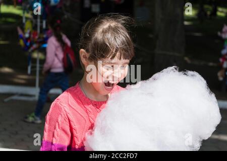 Giovane ragazza che mangia caramelle di cotone nel parco. Foto Stock