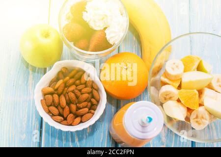 Colazione tradizionale americana ed europea estiva: frutti di bosco, mela alla frutta, fragola, arancia, banana. Tavolo blu chiaro. Foto Stock