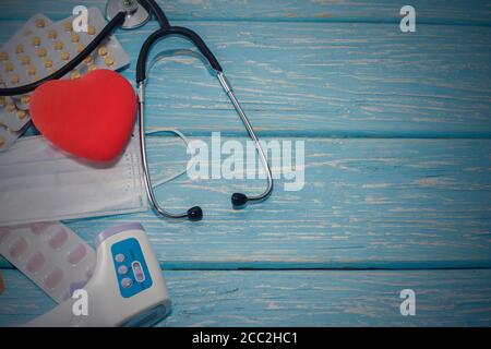 Un cuore con stetoscopio si trova su uno sfondo ligneo. Cuore sano Foto Stock