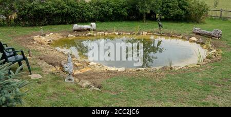 Recentemente completato grande laghetto giardino con primo impianto di piante laghetto e circondato da pietre Cotswold, Colemans Hill Farm, Mickleton, Regno Unito Foto Stock