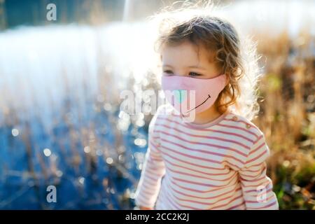 Piccola ragazza con maschera all'aperto in natura, a piedi. Foto Stock