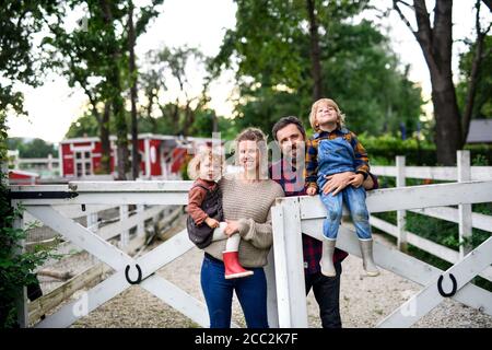 Ritratto di famiglia con bambini piccoli in piedi in fattoria. Foto Stock