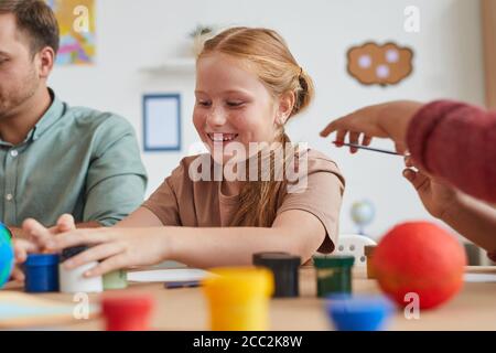 Ritratto di carino foto di pittura ragazza capelli rossi mentre godendo di arte e lezione di artigianato a scuola o centro di sviluppo, copia spazio Foto Stock