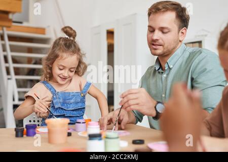 Ritratto di giovani insegnanti di sesso maschile disegno immagini mentre si lavora con bambini a lezione di arte e artigianato in preschool o centro di sviluppo, copia spazio Foto Stock