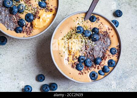 Colazione vegan - ciotola al cioccolato con budino di chia, burro di arachidi e bacche in una ciotola grigia. Foto Stock