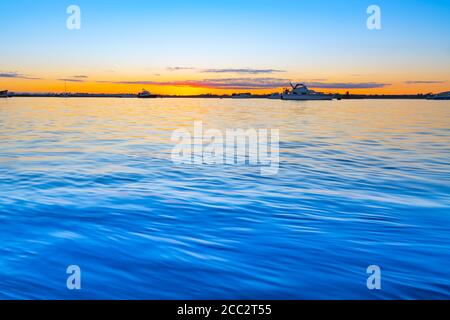 Alba sulle acque blu del porto di Tauranga con intensa luce dorata all'orizzonte. Foto Stock