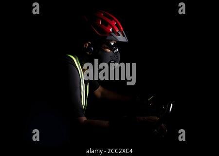 Un ciclista che indossa casco e maschera protettiva Foto Stock