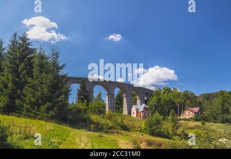 Viadotto ferroviario in pietra a Smrzovka, giorno estivo con cielo blu, montagne Jizera, repubblica Ceca Foto Stock