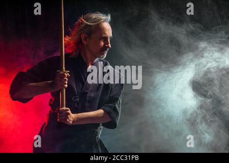 combattente caucasico maturo in abito con spada di bambù shinai , pratica lotta prima delle competizioni. arte marziale giapponese tradizionale concetto. isol Foto Stock