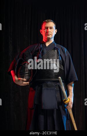 Combattente caucasico maschile kendo in stile tradizionale giapponese di abbigliamento, armatura protettiva, utilizzando shinai. Pratica lotta isolato Foto Stock